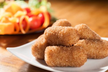 Beyaz kare tepside, ahşap bir arka planda patatesler ve bir sala.