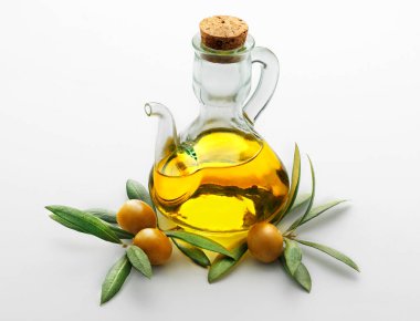 Yeşil zeytin yapraklı zeytin ağacının tabanında şeffaf zeytinyağı dolu cam bir yağ tenekesinin beyaz arka planında yaşam devam ediyor.
