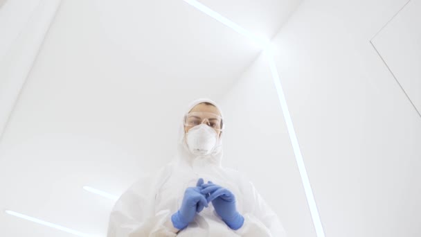 Een mooi meisje in een beschermend medisch pak tijdens de epidemische gemoederen in de witte, moderne gang van het ziekenhuis. De arts onderzoekt de patiënt tijdens de epidemie. — Stockvideo