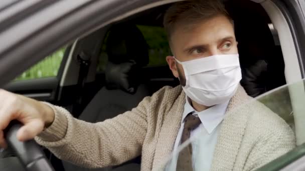 Человек в медицинской маске во время эпидемии, деловой водитель в маске, защита от вируса. Водитель в пиджаке в машине. Коронавирус, инфекция, карантин, ковид-19 — стоковое видео