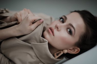 Stüdyoda Avrupa görünümlü güzel bir kızın portresi. Güzel bir kızın ciddi portresi. Kız ceketinin yakasına tutunuyor..