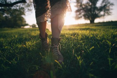 Genç bir kadın çimenlerde yürüyor.