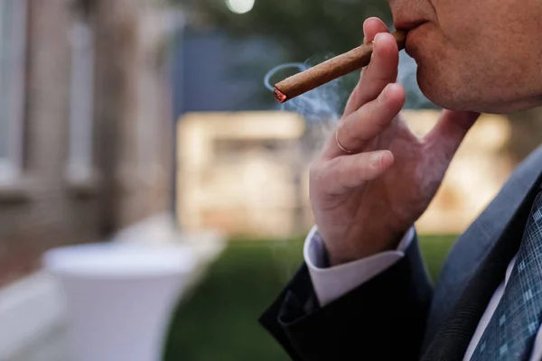 A man smokes a cigar. Close-up, smoke, mouth, cigarette.