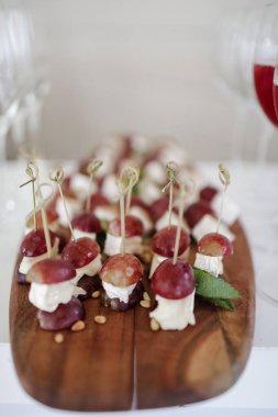 Ahşap bir tahtanın üzerinde üzümlü ve mozarellalı kanepeler. Yemek servisi.. 