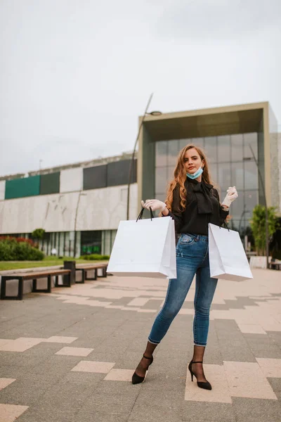 Egy Gyönyörű Fehér Maszkban Kesztyűben Áll Egy Bevásárlóközpont Előtt Táskákkal — Stock Fotó