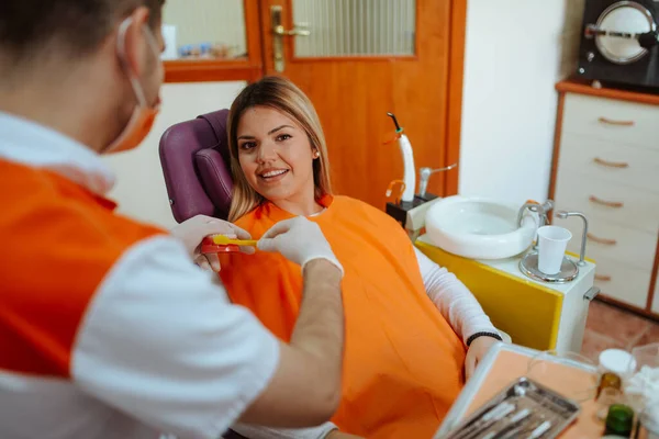 Portrait of a beautiful caucasian woman on a chair and a young dentist in a dental office