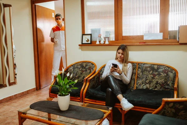 Kafkasyalı genç bir dişçi, ofise girmek için elinde telefon olan beyaz bir kadını arıyor.
