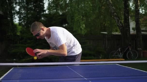 Игрок в настольный теннис готовится к подаче. Игрок в саду с мячом — стоковое видео