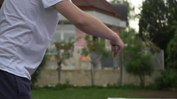 Чоловік грає у настільний теніс у саду. Гравець вдарив м'яч у пінг-понг грі. — стокове відео