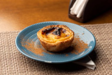 Portekiz kremalı turtası - Pastel de Belem ve Pastel de Nata mavi seramik ve ahşap masa üzerinde