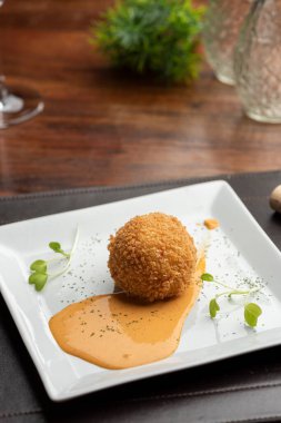 Arancini risotto ve sıcak domates sosu üzerine doldurulmuş mozzarella ile bulanık arka planı olan bir tabağa konur.