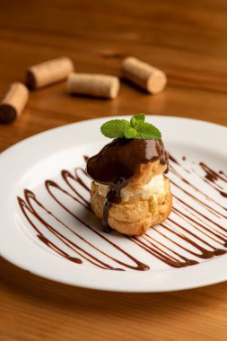 Beyaz tabakta vanilyalı dondurmayla doldurulmuş profiteroller.