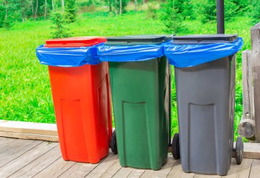 Mavi plastik torbalı üç çöp kutusu.