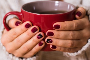 Kırmızı manikür kırmızı bir fincan çay tutan kadınla