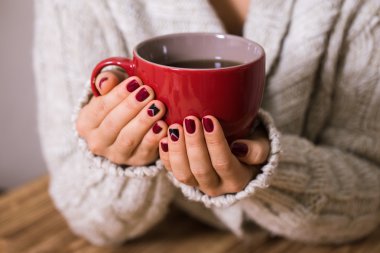 Kırmızı manikür kırmızı bir fincan çay tutan kadınla