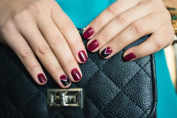 Female nails with red nail polish and a beautiful black handbag