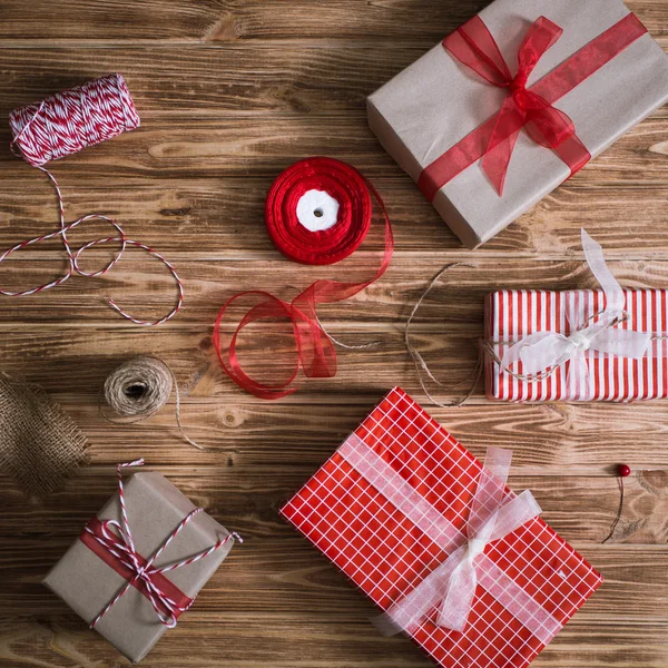 Regalos de Navidad en papel y atados con hilos rojos y blancos y una taza de té sobre fondo de madera —  Fotos de Stock