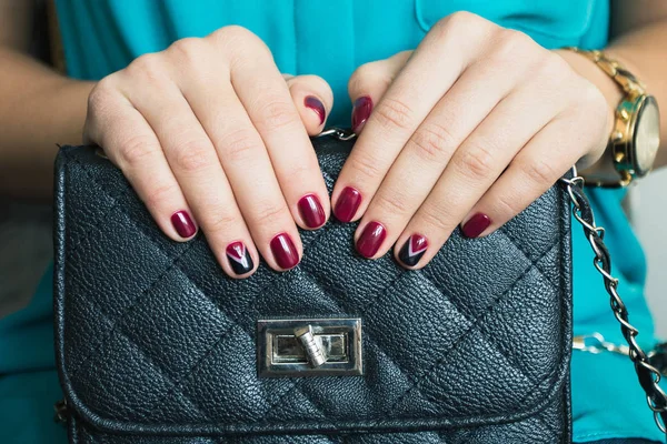 Жіночі нігті з червоним лаком для нігтів і красивою чорною сумкою — стокове фото