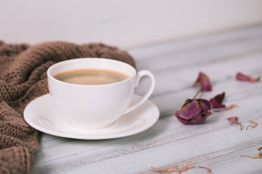 Kış kapuçino kompozisyon. Köpük ve örme eşarp, beyaz tahta arka plan ile Blue kahve Kupası Üstten Görünüm