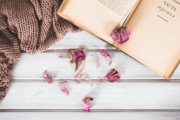 Suszone kwiaty z książką i ciepłym szalikiem na podłoże drewniane — Zdjęcie stockowe