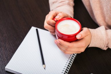 Kırmızı bir fincan kahve tutan kadın. Kırmızı kurdele ve beyaz dizüstü bilgisayar hediye kutusu