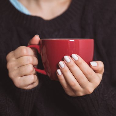 Kadın kırmızı bir fincan çay tutan güzel manikür ile