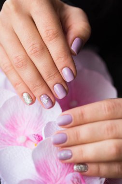 El bir pembe çiçekler üzerinde manikürlü tırnaklar