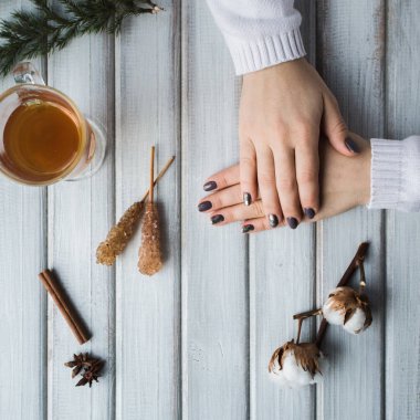 Ahşap masanın üzerinde bir fincan çay tutan bir kadın..