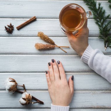 Ahşap masanın üzerinde bir fincan çay tutan bir kadın..