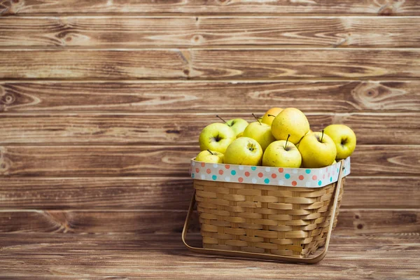 Ahşap arka plan üzerinde bir sepet içinde altın elma — Stok fotoğraf
