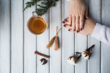 Ahşap masanın üzerinde bir fincan çay tutan bir kadın..