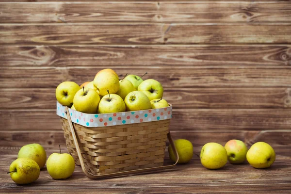 Zlatá jablka v koši na dřevěné pozadí — Stock fotografie