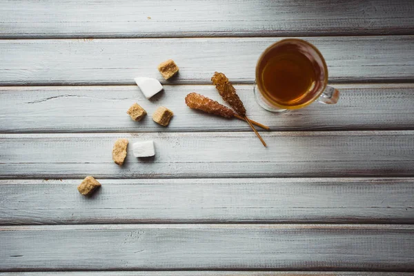 Fincan çay ve şeker kamışı. Ahşap arka plan üzerinde.