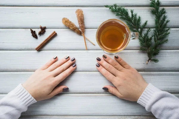 Ahşap masanın üzerinde bir fincan çay tutan bir kadın..