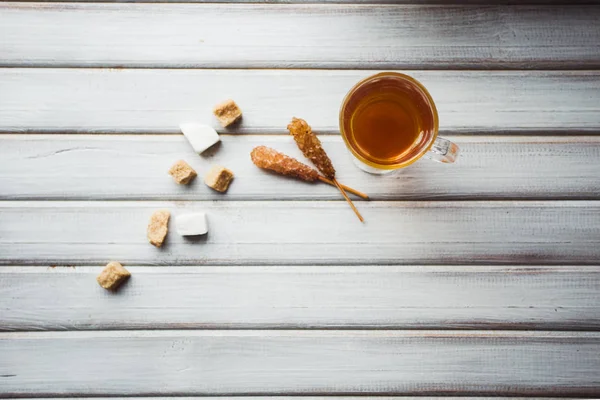 Tazza di tè e zucchero di canna. Su sfondo di legno . — Foto Stock