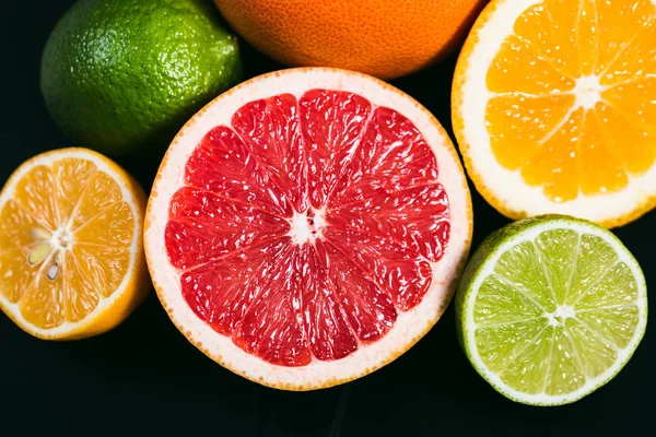 Frisse citrus stihli. Oranje op een zwarte achtergrond, citroenen, limoenen (lemmetjes) en grapefruit — Stockfoto