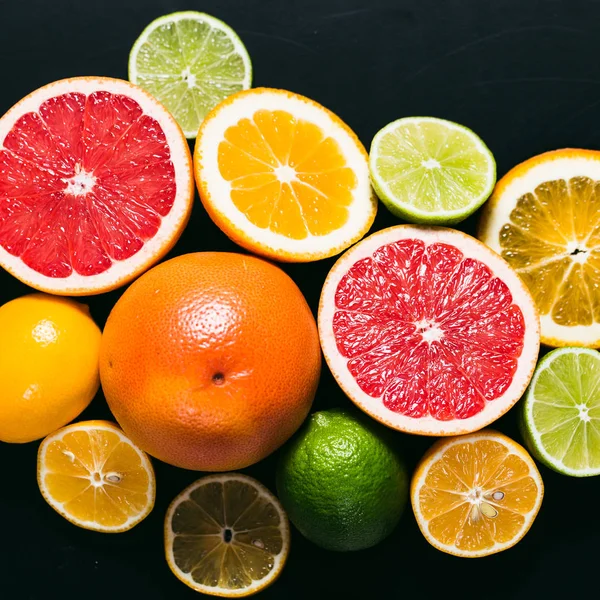 Frisse citrus stihli. Oranje op een zwarte achtergrond, citroenen, limoenen (lemmetjes) en grapefruit — Stockfoto