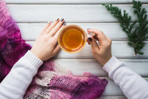 Ahşap masanın üzerinde bir fincan çay tutan bir kadın..