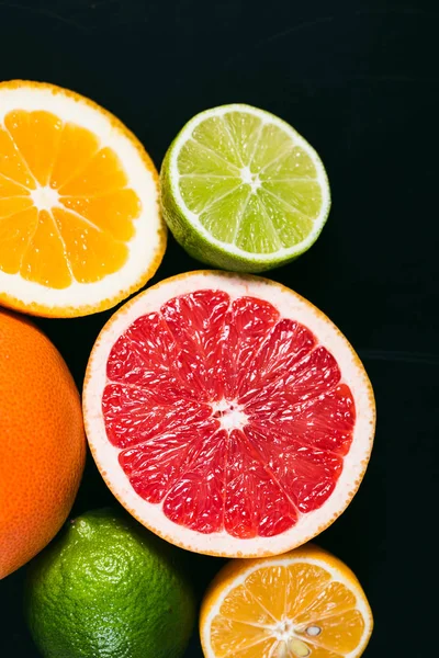 Frisse citrus stihli. Oranje op een zwarte achtergrond, citroenen, limoenen (lemmetjes) en grapefruit — Stockfoto