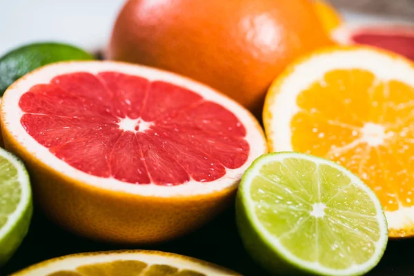 Frisse citrus stihli. Oranje op een zwarte achtergrond, citroenen, limoenen (lemmetjes) en grapefruit — Stockfoto