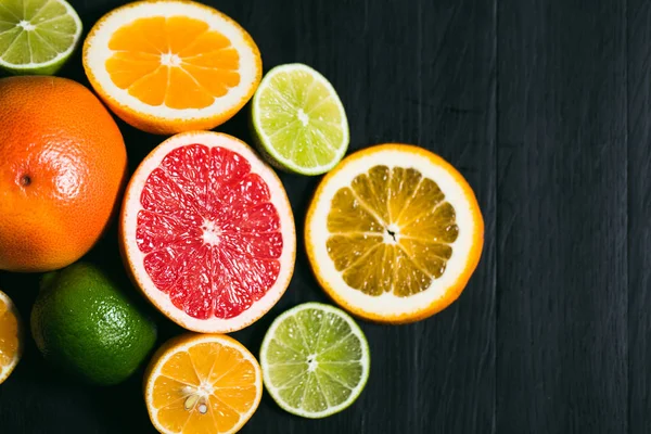 Frisse citrus stihli. Oranje op een zwarte achtergrond, citroenen, limoenen (lemmetjes) en grapefruit — Stockfoto