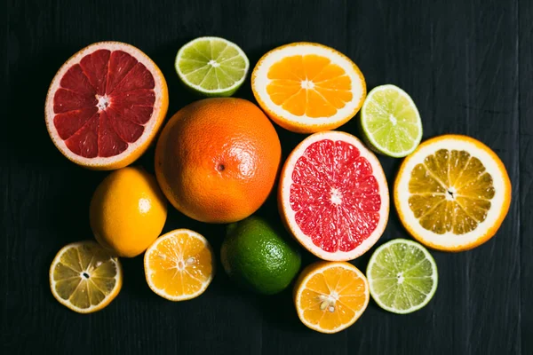 Frisse citrus stihli. Oranje op een zwarte achtergrond, citroenen, limoenen (lemmetjes) en grapefruit — Stockfoto