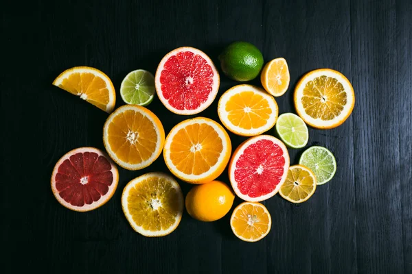 Frisse citrus stihli. Oranje op een zwarte achtergrond, citroenen, limoenen (lemmetjes) en grapefruit — Stockfoto