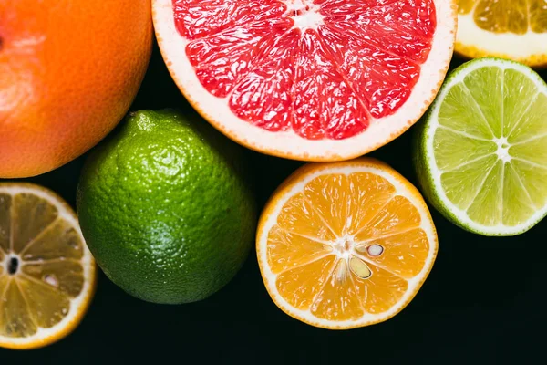 Frisse citrus stihli. Oranje op een zwarte achtergrond, citroenen, limoenen (lemmetjes) en grapefruit — Stockfoto