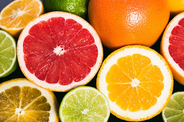 Frisse citrus stihli. Oranje op een zwarte achtergrond, citroenen, limoenen (lemmetjes) en grapefruit — Stockfoto