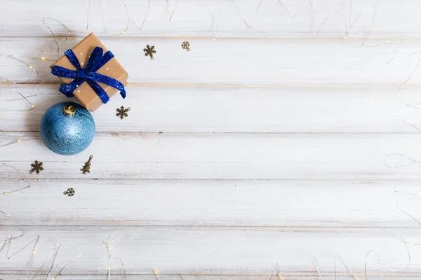 Scatola regalo di Natale e ramo albero di Natale e palla giocattolo e cono su sfondo di legno bianco — Foto Stock
