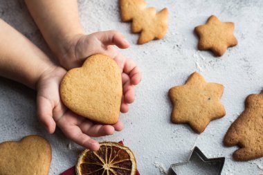 Çocuk elinde kalp şeklinde zencefilli bir ekmek tutuyor.
