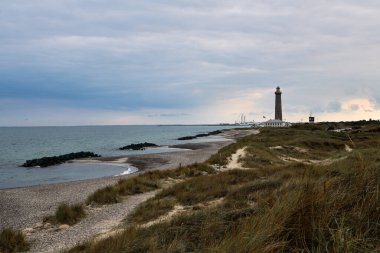 Resimli yazı, Skagen, Jutland, Danimarka, 08-29-2018. Skagen (Danimarka, Kuzey Jutland) yakınlarındaki Skagerrak (Kuzey Denizi) ve Kattegat (Baltık Denizi) kavşağında deniz feneri Grenen (Gri Kule olarak adlandırılır).)