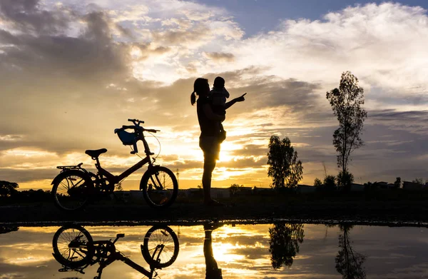 Spiegelung Silhouette der Mutter mit ihrem Kleinkind gegen die Sonne — Stockfoto