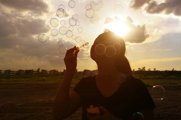 Ein südostasiatisches Mädchen bläst bei Sonnenuntergang Blasen in die Luft — Stockfoto